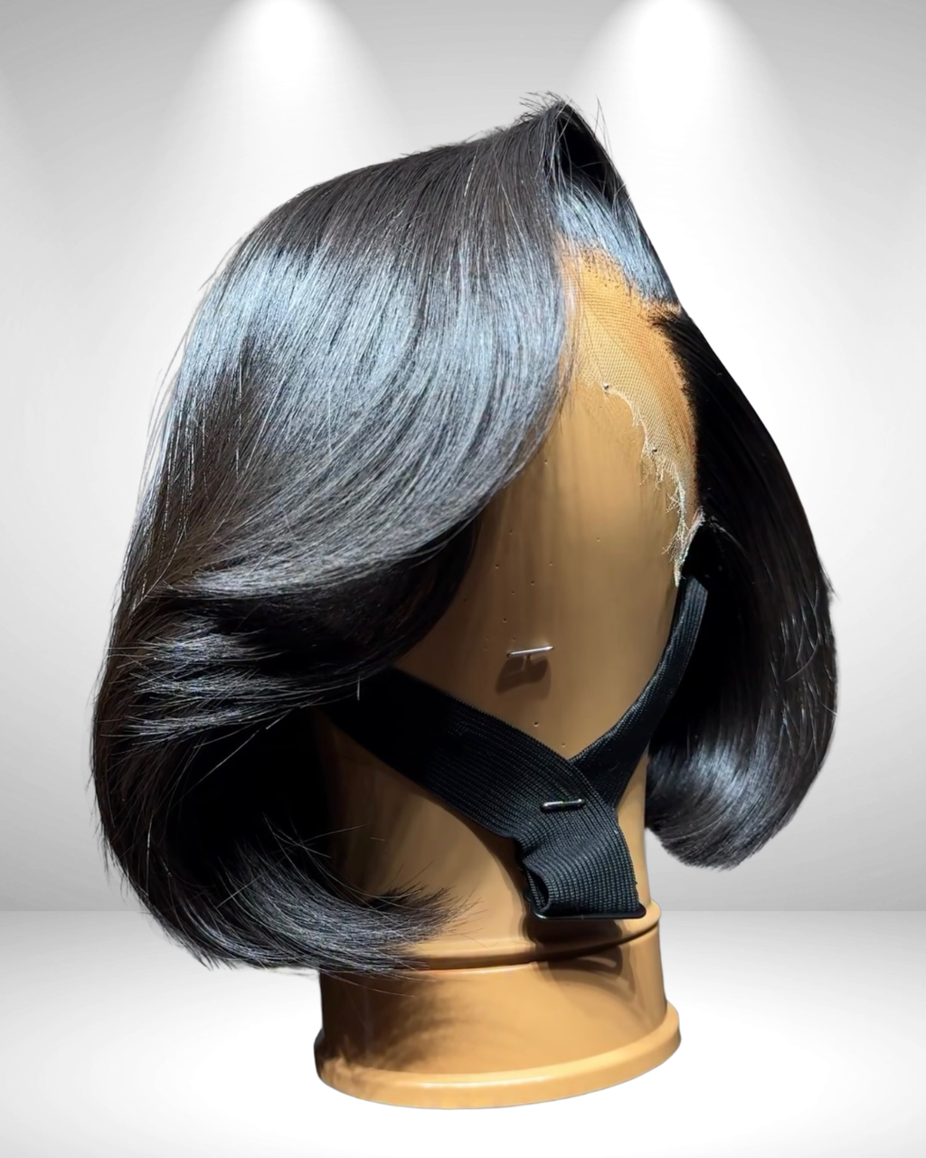 Black wig on a mannequin head against a white background