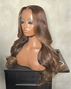 Brown wig on a mannequin head against a neutral background