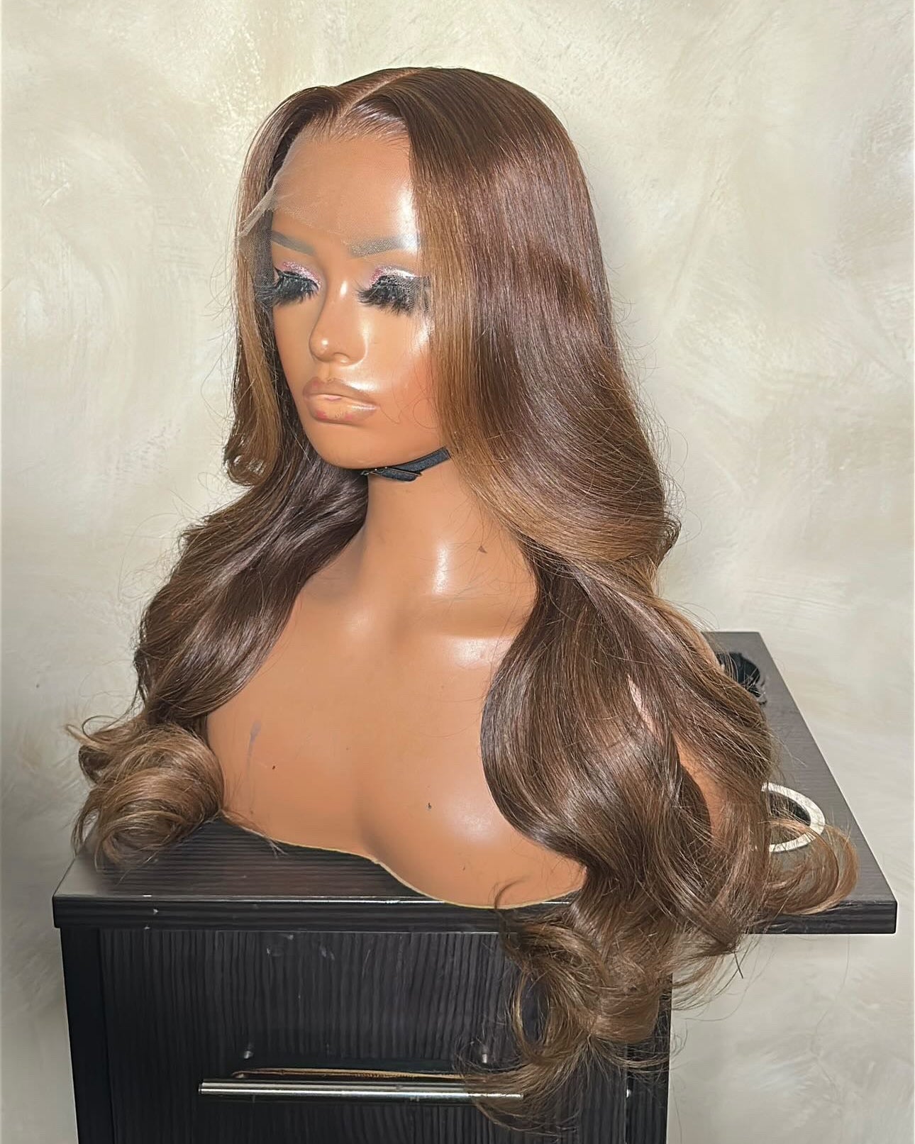 Brown wig on a mannequin head against a neutral background