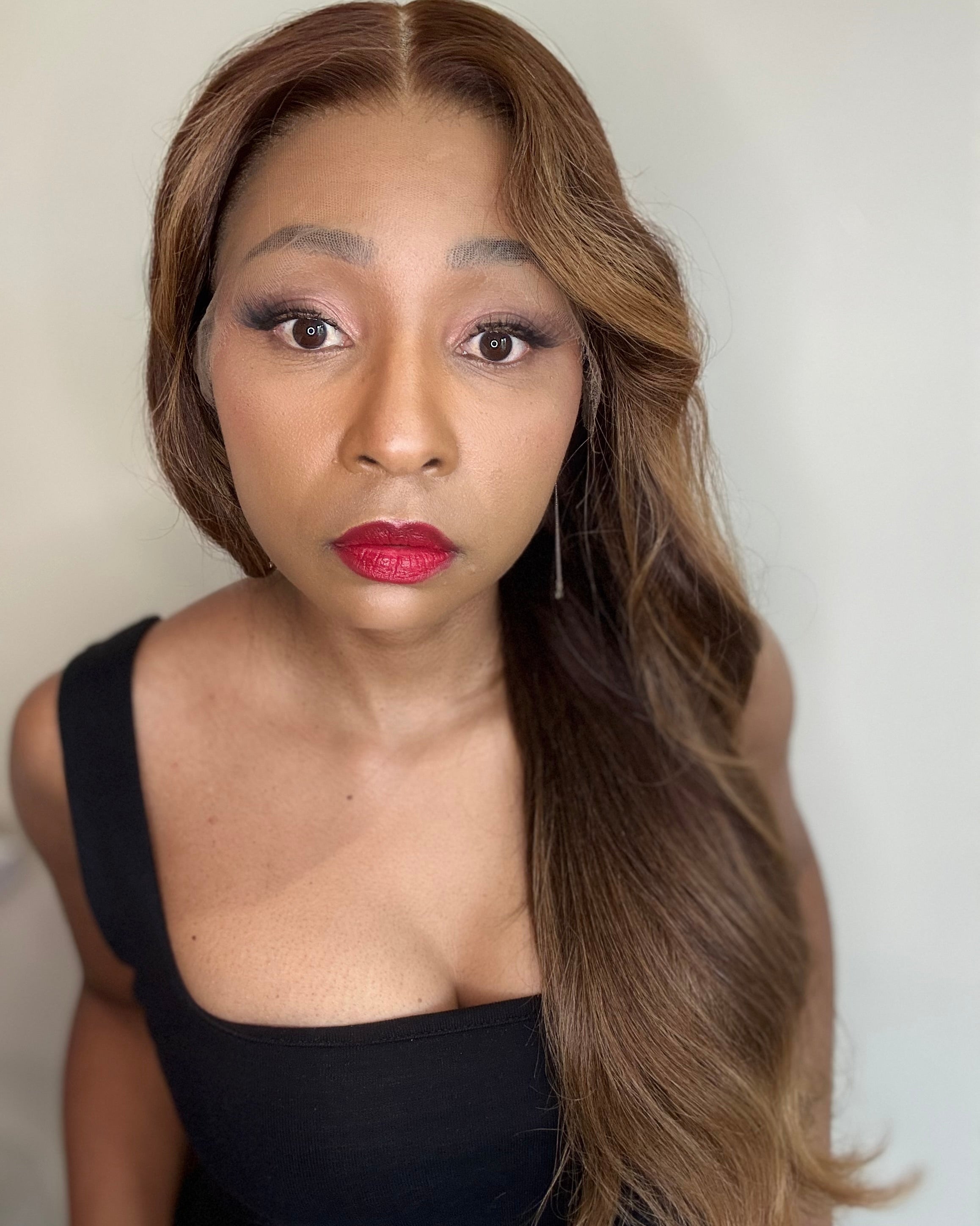 Woman with long, wavy hair wearing a black top against a plain background