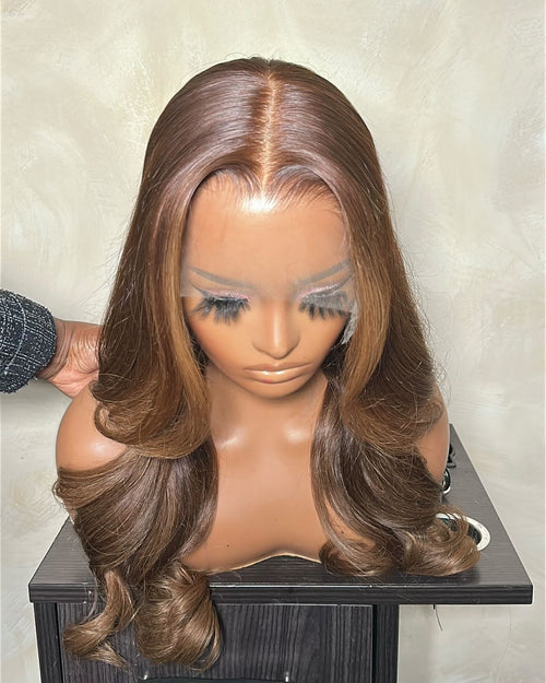 Brown wig on a mannequin head against a neutral background