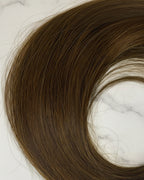 Soft ash-brown hair extensions on a white background