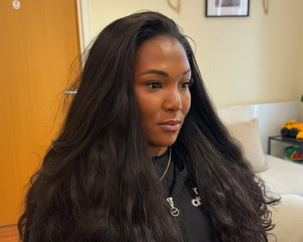 Woman with long, wavy hair in a room with a couch and a plant in Nottingham.