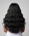 Person with long, wavy black Indian raw hair flip-over wig on a plain background