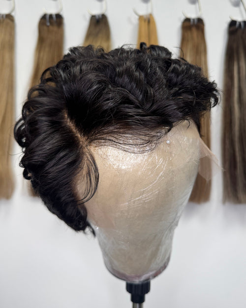 Top view of Lyra virgin full lace curly pixie wig on a mannequin stand showing the full lace cap construction and natural black curl perimeter