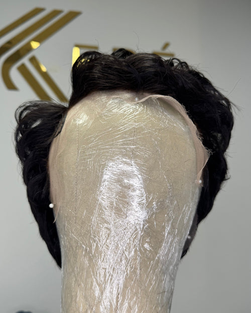 Front view of Lyra virgin full lace curly pixie wig showing natural curl volume and texture in natural black 1B against a Keré Hair Co. UK branded background