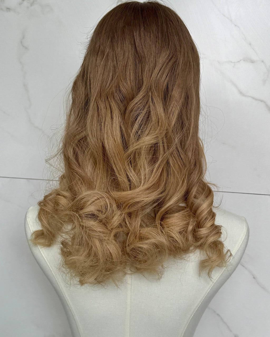 Blonde wig on a mannequin head against a white marble background