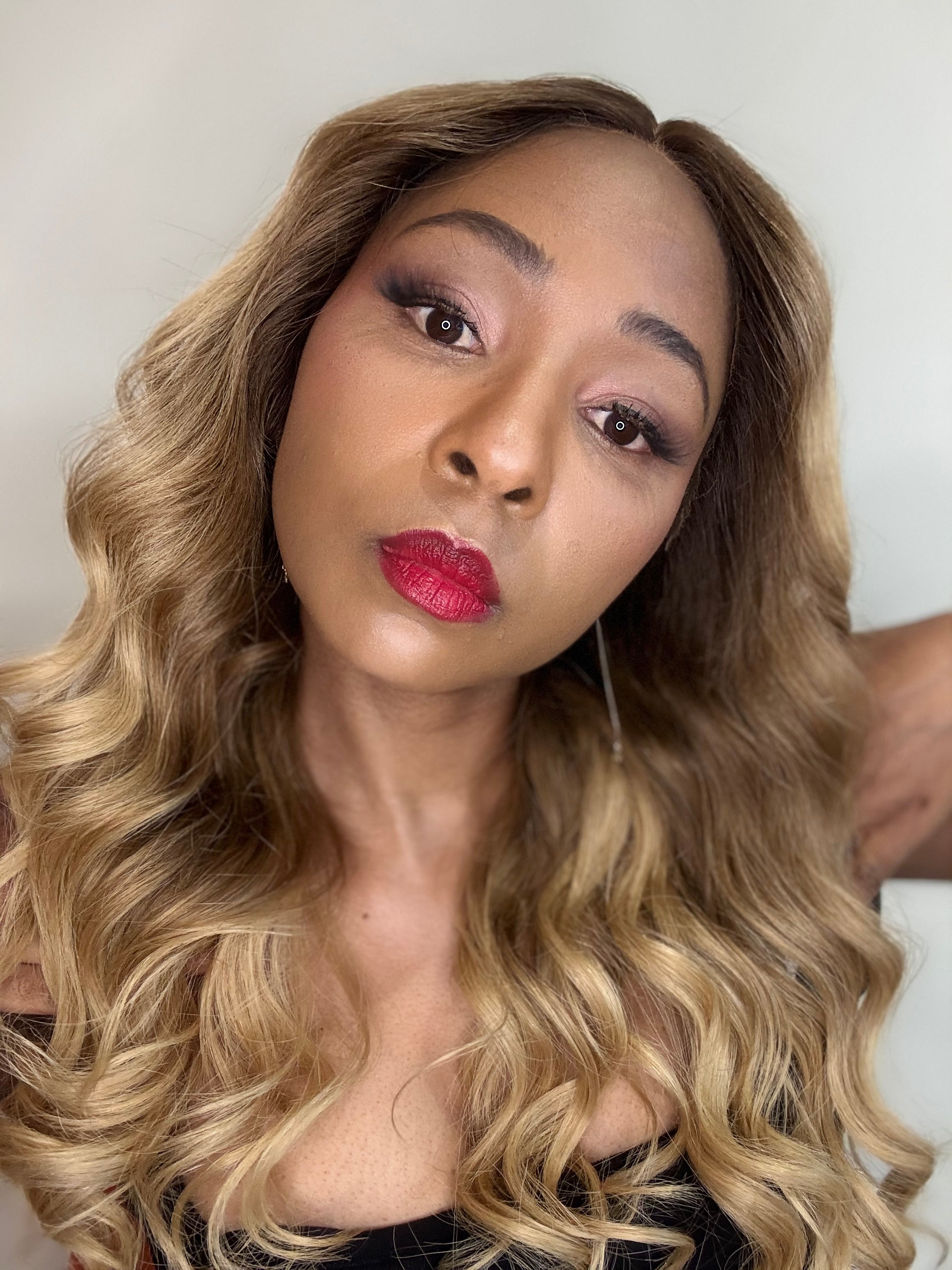 Woman with styled hair and red lipstick against a neutral background