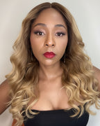 Woman with long, wavy blonde hair wearing a black top against a neutral background