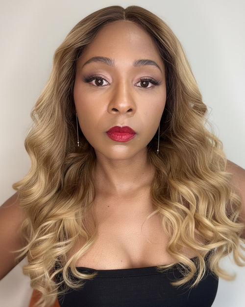 Woman with long, wavy blonde hair wearing a black top against a neutral background