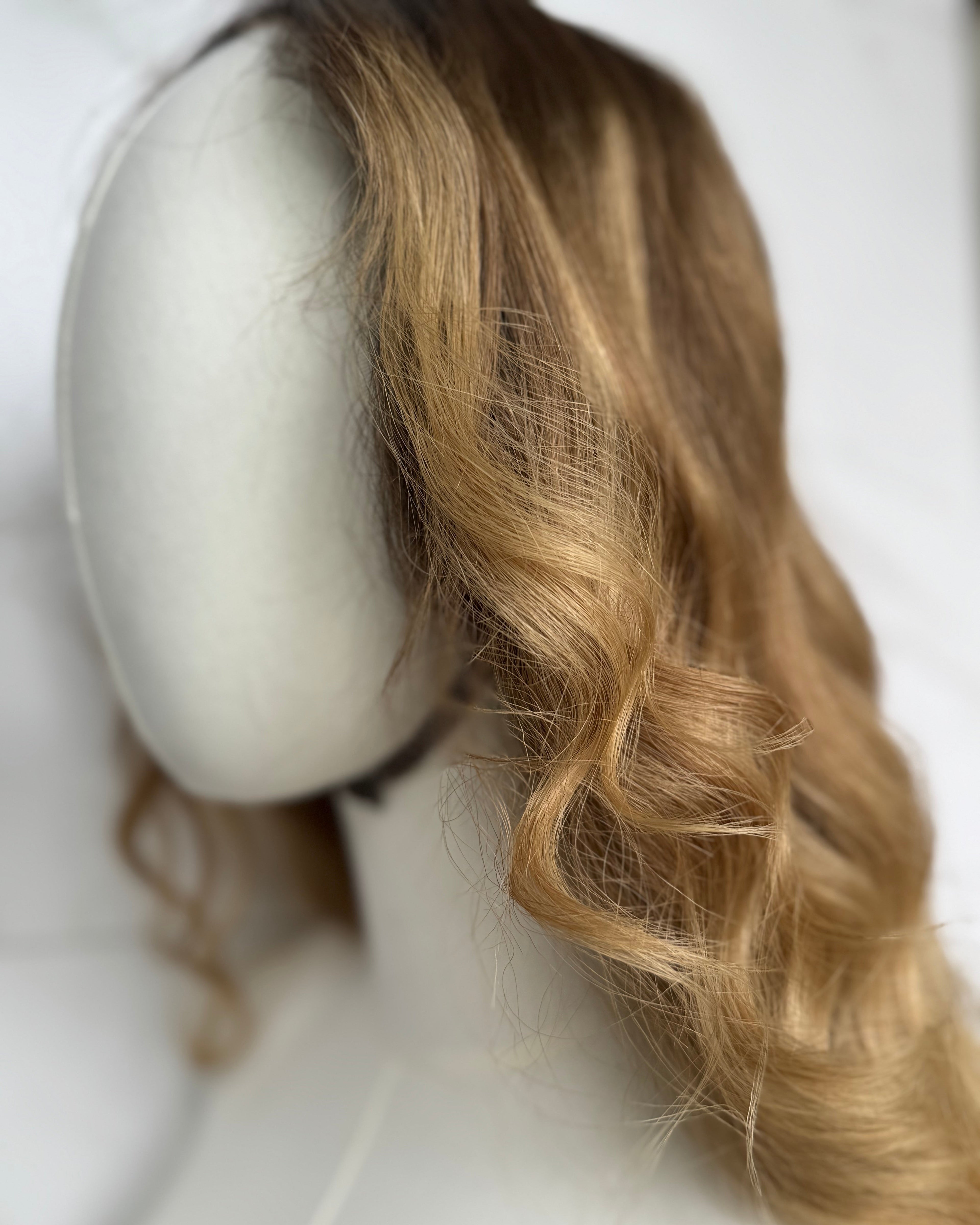 Blonde wig on a mannequin head against a white background