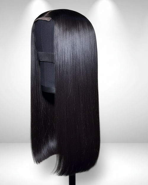 Side view of Noire natural black Cambodian raw hair glueless wig held by hand, showing bone-straight 1B hair and HD lace cap construction.