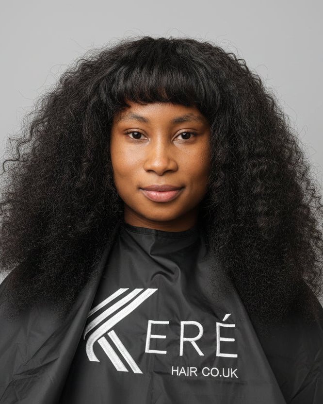 Person wearing a black hairdressing cape with Kere Hair Co. UK logo on a gray background