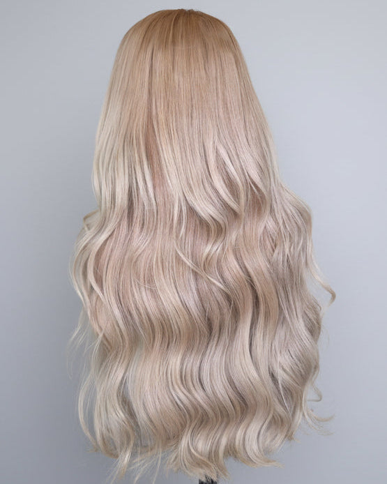 Blonde wig with wavy Vietnamese raw hair on a mannequin head against a plain background.
