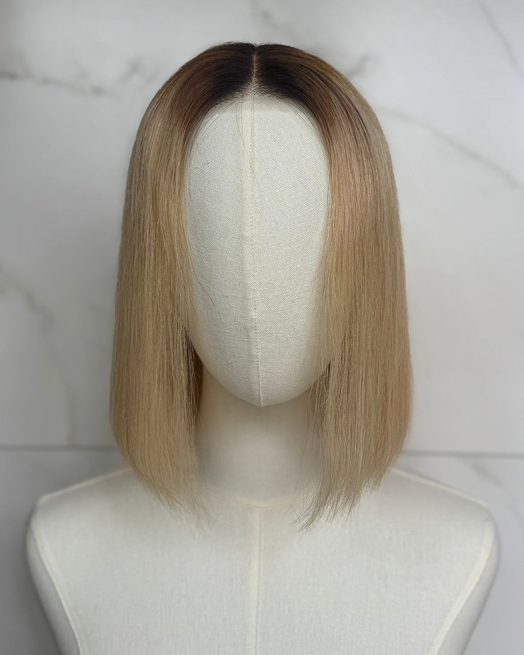 Blonde wig on a mannequin head against a marble background