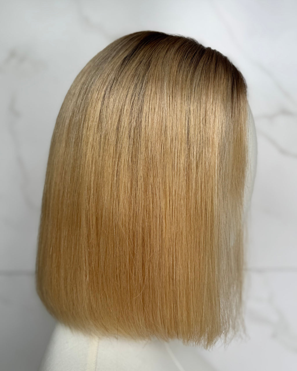 Blonde wig on a mannequin head against a white background