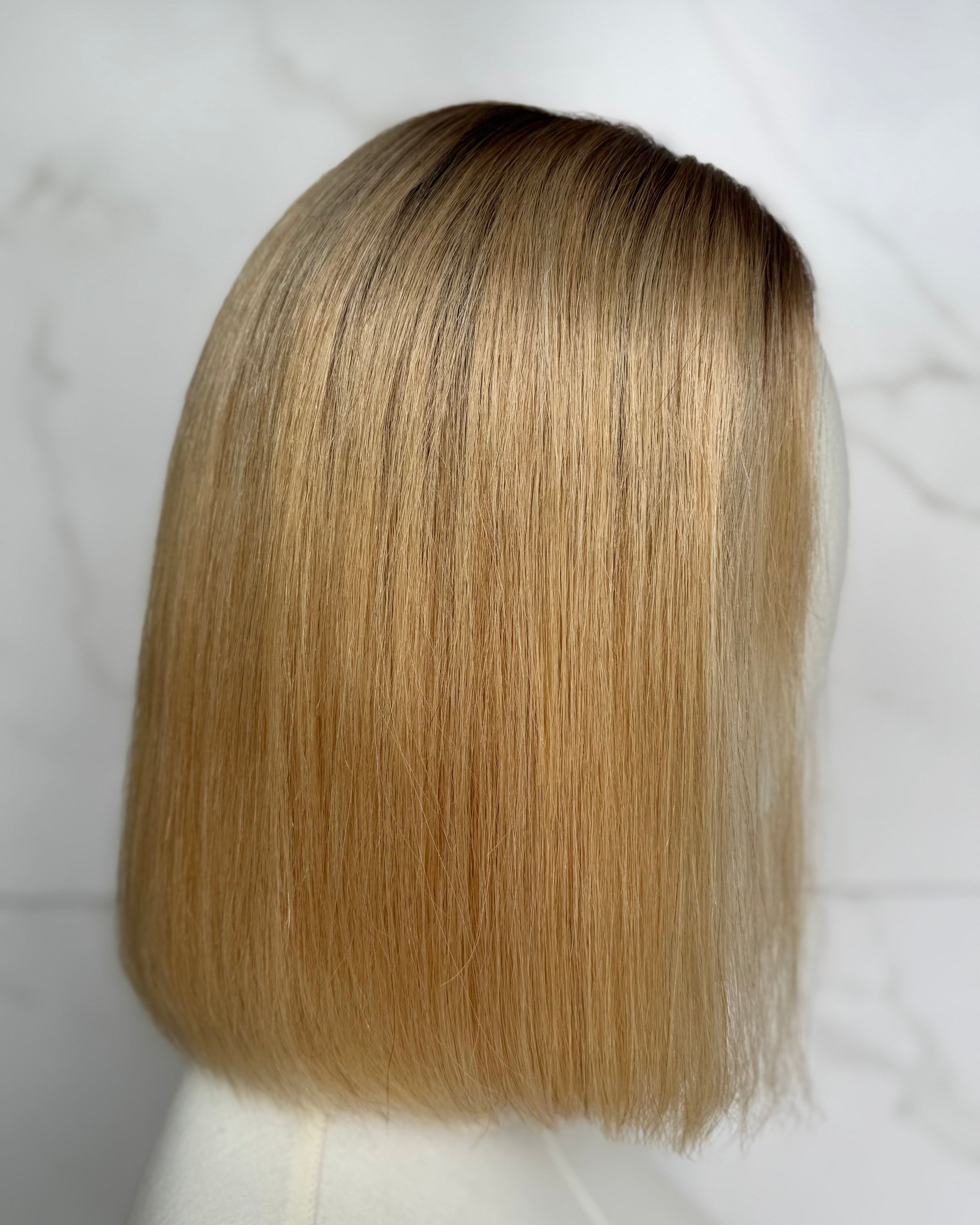 Blonde wig on a mannequin head against a white background